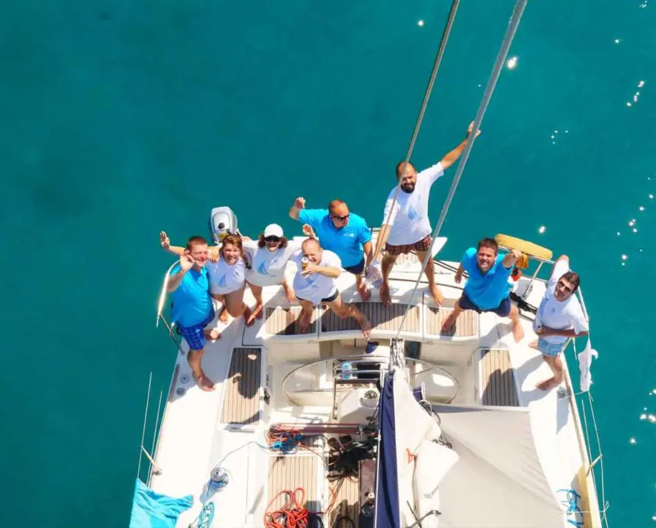 Das SabeeApp-Team winkt an Deck eines Segelboots während eines Teamausflugs