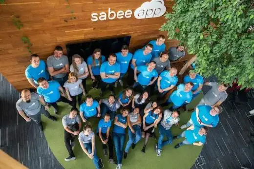 Das Team von SabeeApp vor dem Firmenlogo im Büro in Budapest