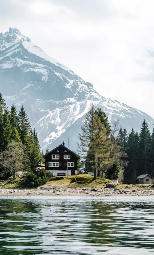 Schweizer Chalet am Seeufer vor schneebedeckten Bergen