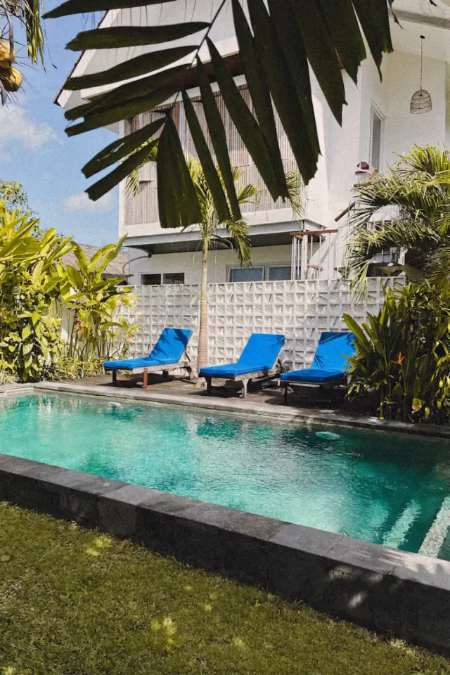 Liegestühle am Pool unter blauen Sonnenschirmen