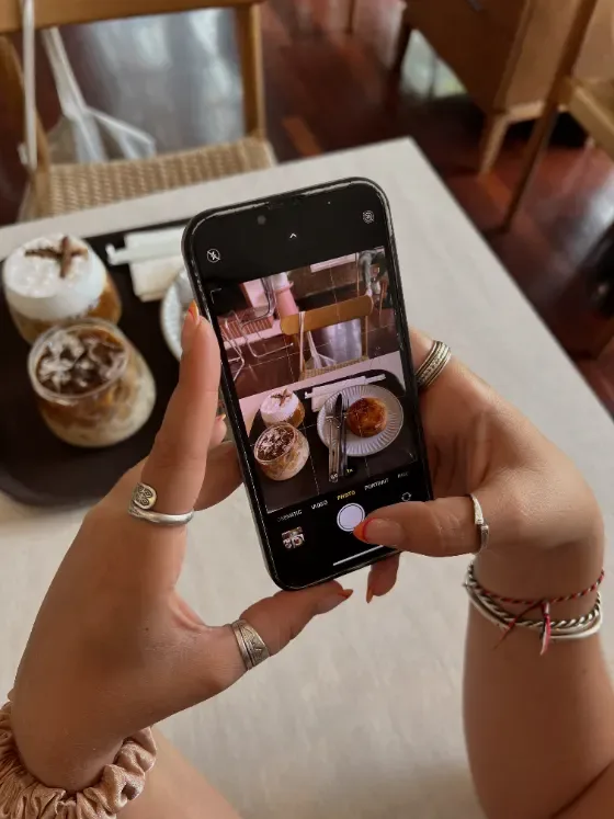 Hand fotografiert Kaffee und Gebäck mit dem Smartphone