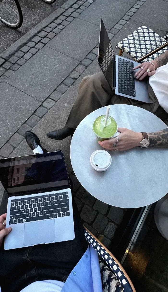 Zwei Personen arbeiten an Laptops an einem Café-Tisch