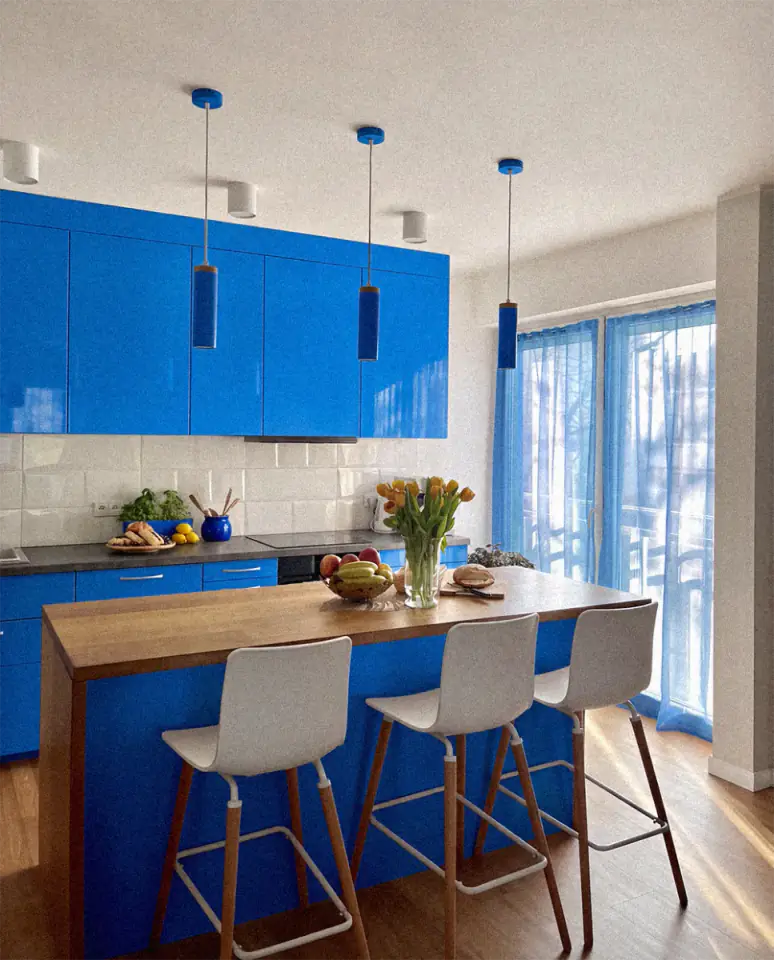 Küche eines Apartments mit blauen Schränken und Kochinsel aus Holz